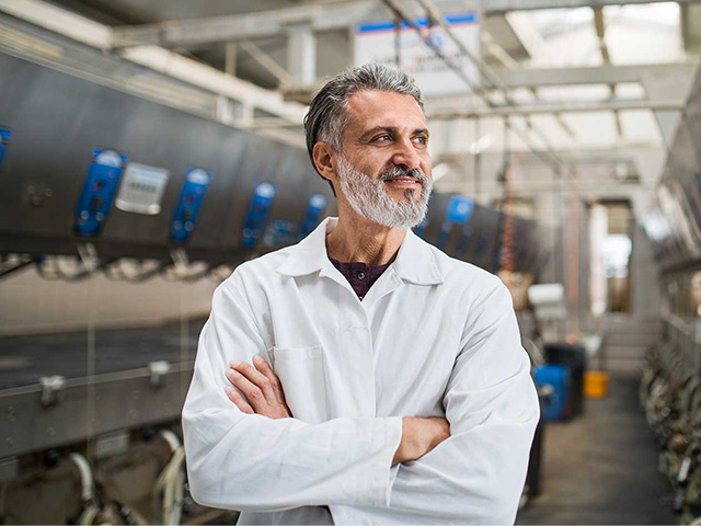 A man in a lab coat standing in an agriculture manufacturing environment.